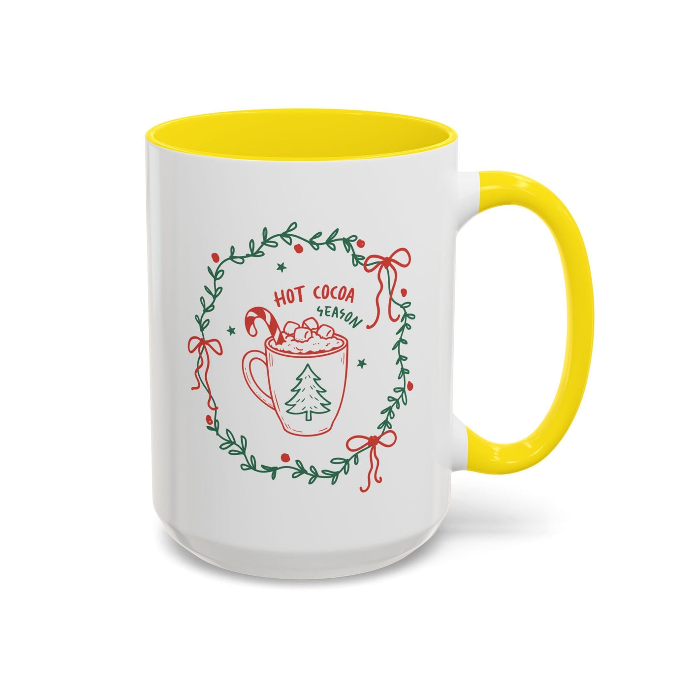White ceramic mug with yellow handle and interior featuring festive hot cocoa season design with greenery wreath
