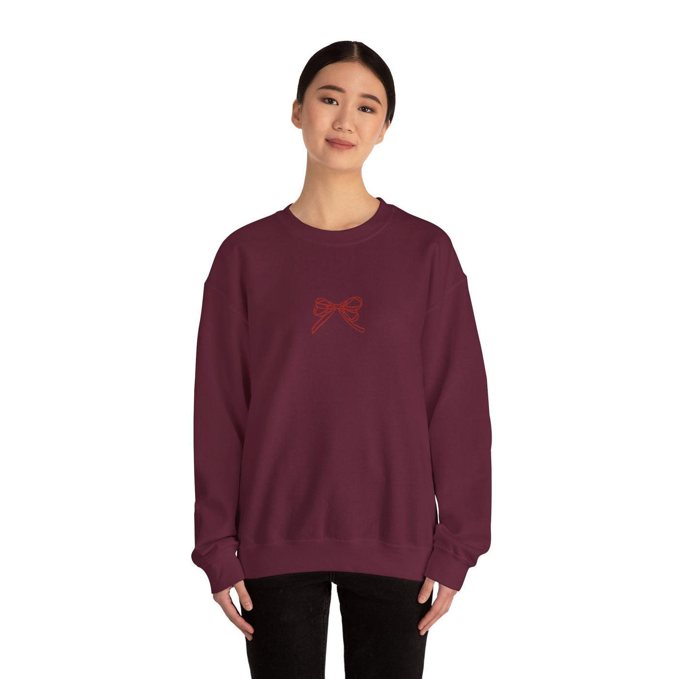 Woman wearing maroon Holiday Bow Crewneck Sweatshirt with small bow design on front, festive holiday apparel for adults