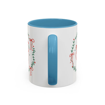 White ceramic mug with blue interior and handle featuring festive red and green holiday wreath design