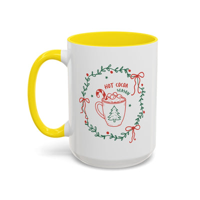 white ceramic mug with yellow interior and handle featuring hot cocoa season holiday design with greenery wreath