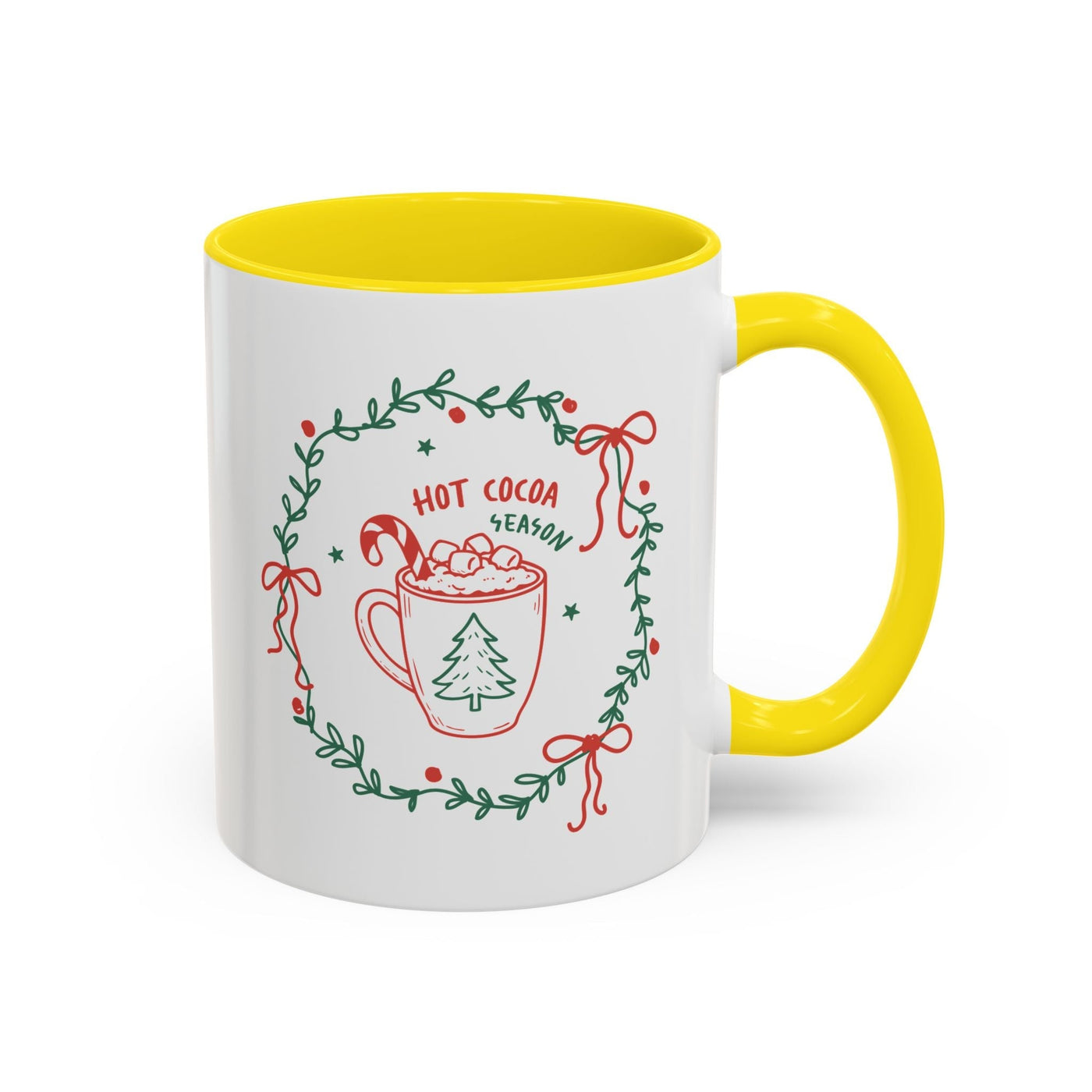 Ceramic mug with white exterior, yellow interior, and hot cocoa season design with greenery and festive accents