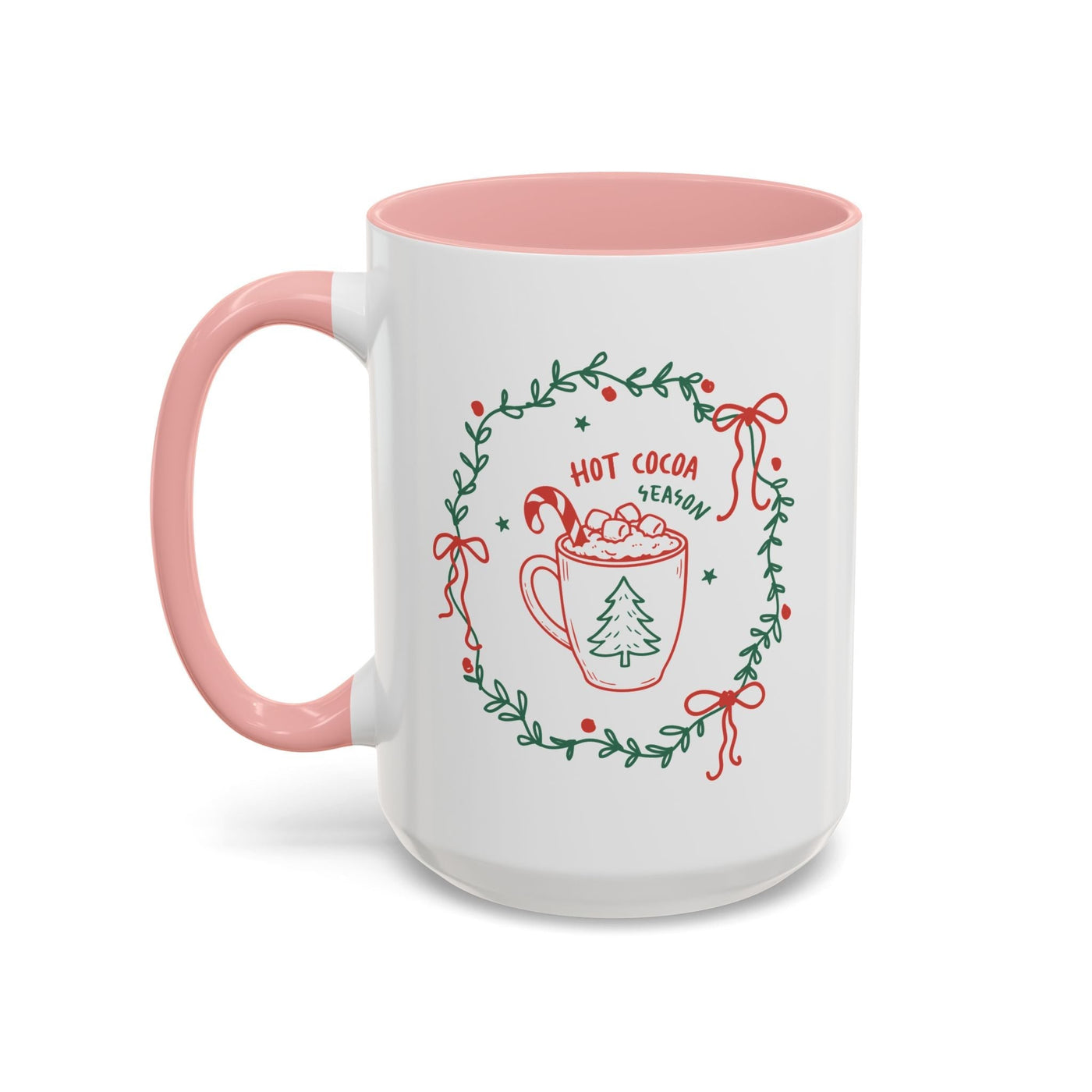 white ceramic mug with pink handle and interior, festive hot cocoa season design with greenery wreath and candy cane illustration