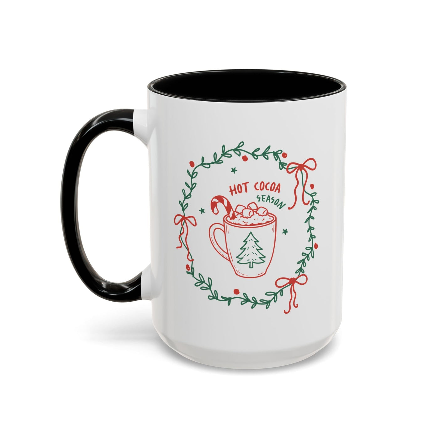 White ceramic mug with black handle and interior, festive hot cocoa season design with greenery wreath, red and green accents