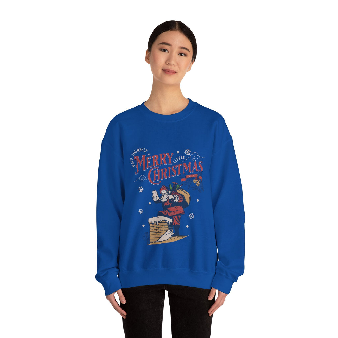 Woman wearing blue Vintage Santa Crewneck sweatshirt with Santa climbing into chimney holding gift bag and Merry Christmas text