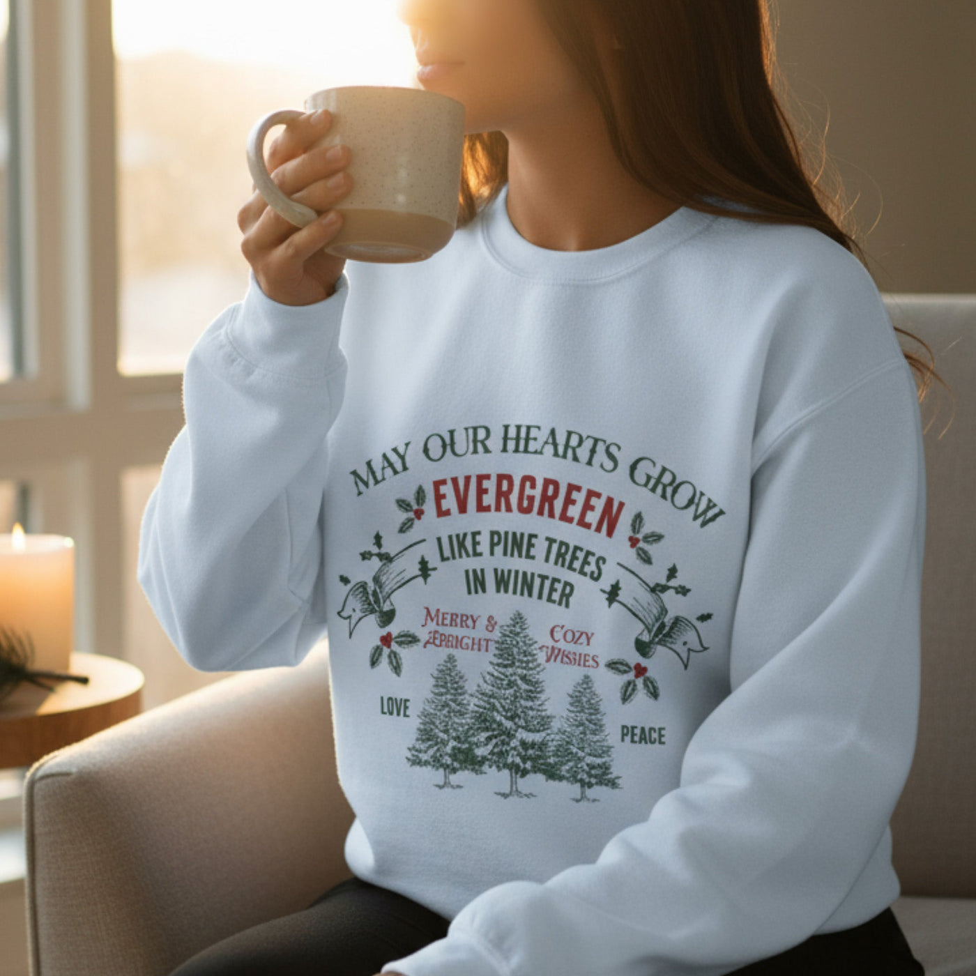 woman wearing white Christmas crewneck sweatshirt with evergreen pine tree holiday design sipping coffee indoors