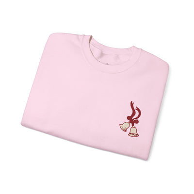 Folded pink vintage Merry Christmas crewneck sweatshirt with bell and Santa sleigh holiday design