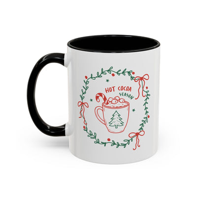 Ceramic mug with hot cocoa season design, white exterior and black handle and interior, festive greenery wreath decoration