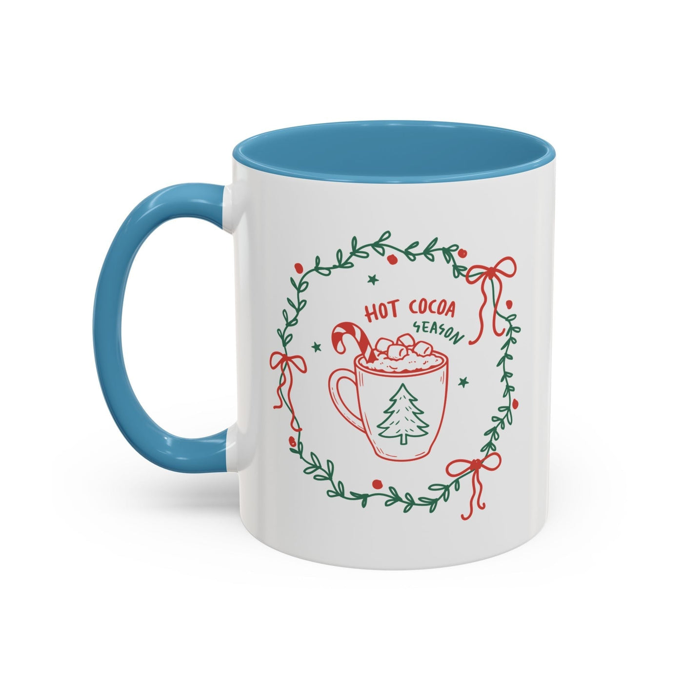 White ceramic mug with blue handle and interior featuring festive hot cocoa season wreath design
