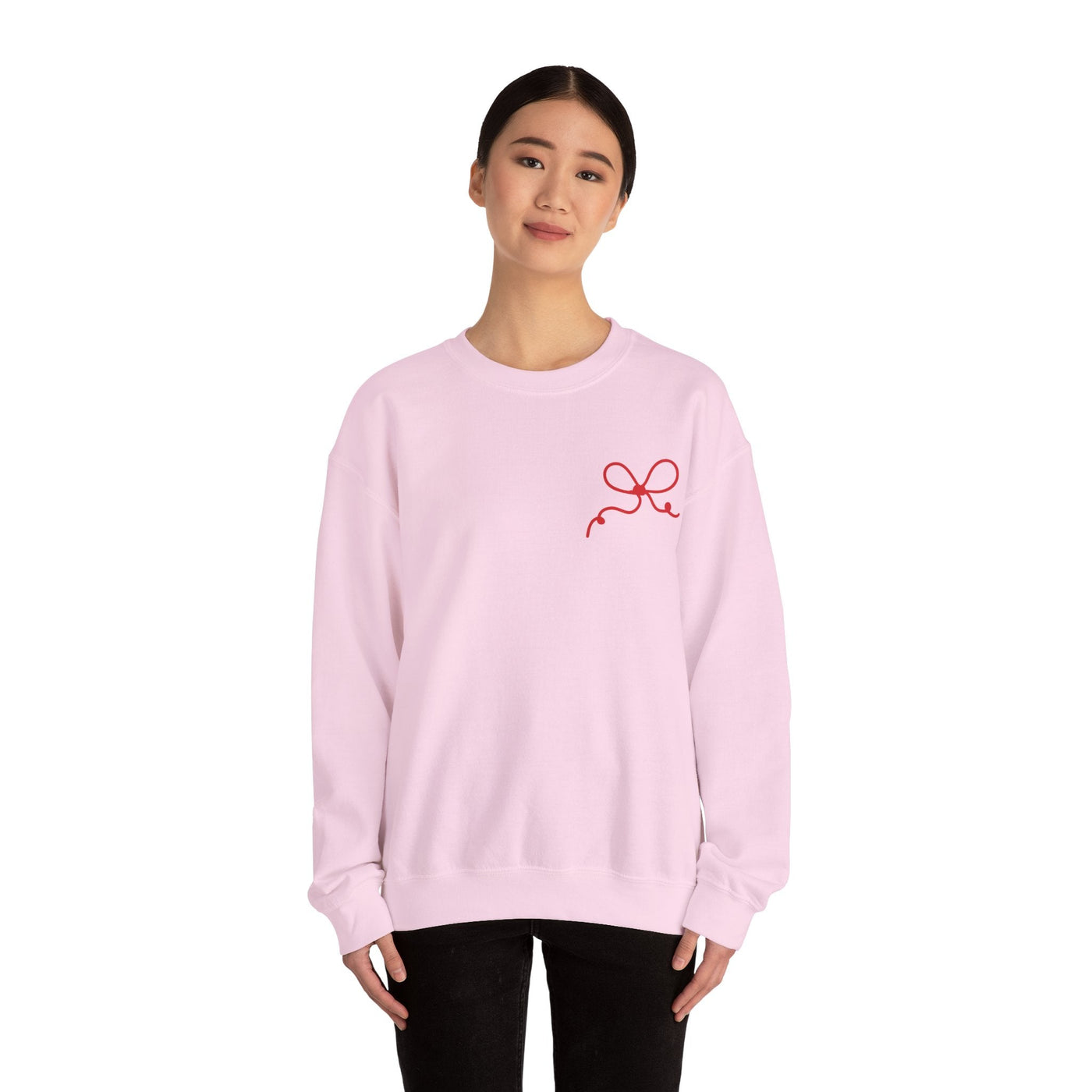 Woman wearing light pink Coquette Bow Crewneck Sweatshirt with red bow design on front, long sleeves, and ribbed collar