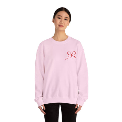 Woman wearing light pink Coquette Bow Crewneck Sweatshirt with red bow design on front, long sleeves, and ribbed collar