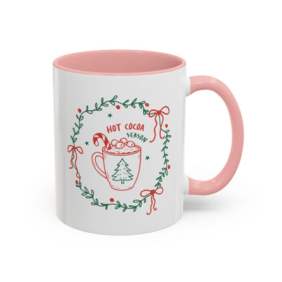 white ceramic mug with pink interior and handle featuring hot cocoa season festive design with greenery wreath and candy cane illustration