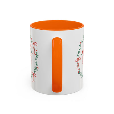 White ceramic mug with orange interior and handle featuring festive greenery and red ribbon design