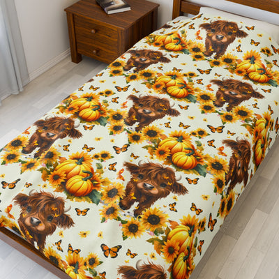 Highland Cow Velveteen Blanket with sunflowers, pumpkins, and butterflies on a cozy farmhouse bedspread